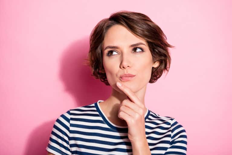 Frau hält sich nachdenklich Hand ans Kinn - Deckbiss Behandlung