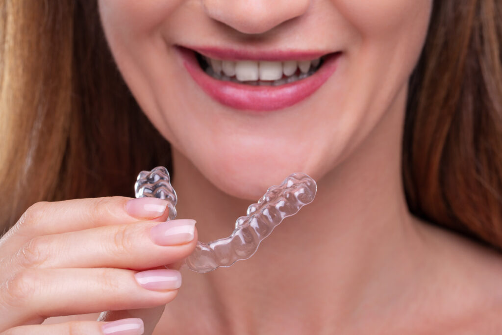 Woman is holding aligners in front of her face - nighttime clear aligners