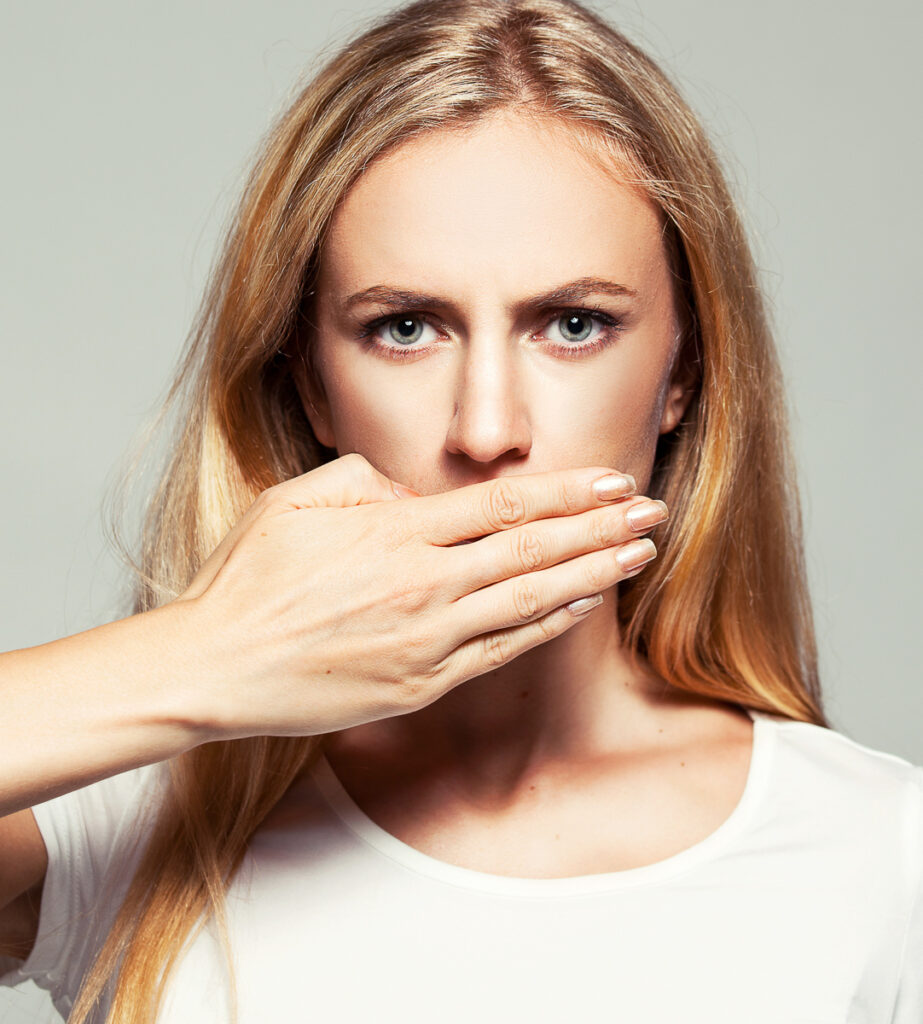 Vorderzähne schief: Junge Frau hält sich die Hand vor den Mund