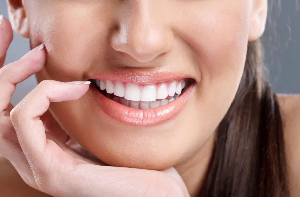 Ung kvinna ler strålande - hur får man raka tänder?