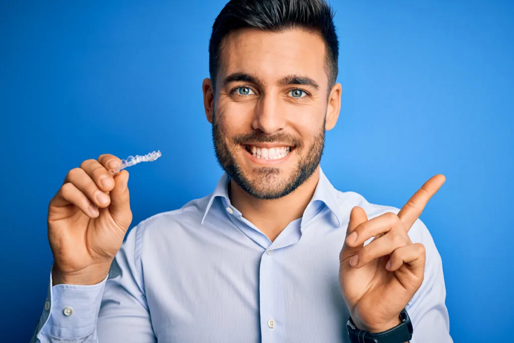 Young man holding aligner - drinking with Invisalign 