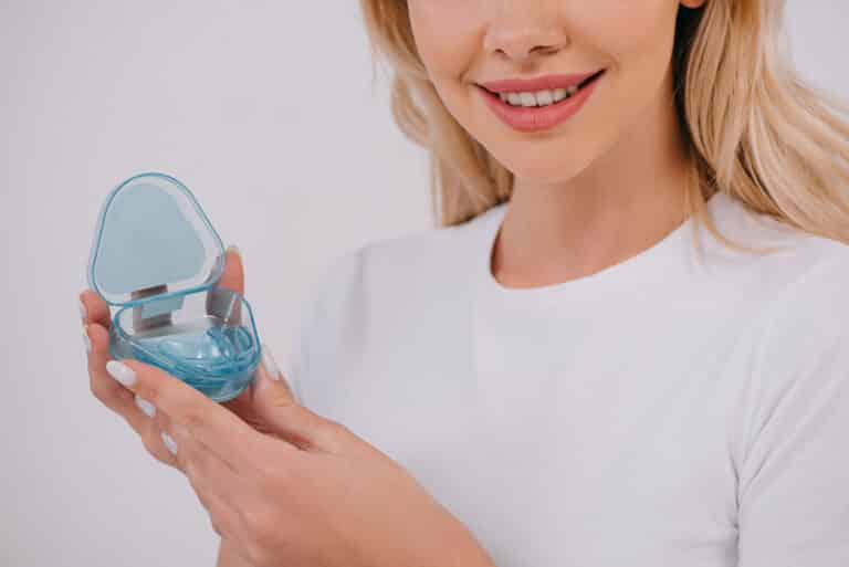 Frau hält Zahnspangen Dose in der Hand - schiefe Zähne nach der Zahnspange