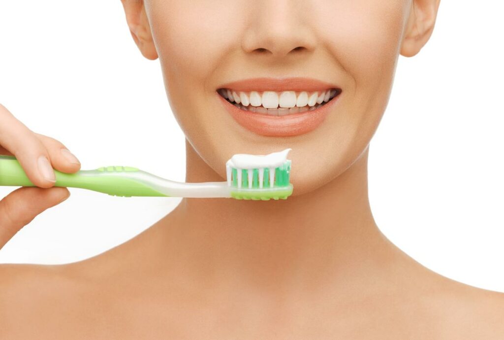 Woman brushes her teeth - manual toothbrush or electric toothbrush